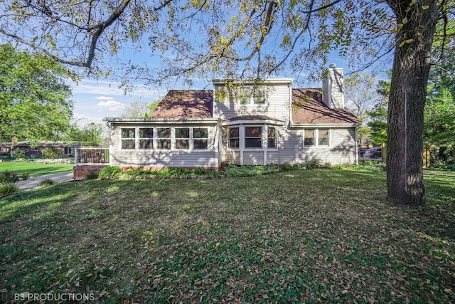 rear view of house with a sunroom and a lawn