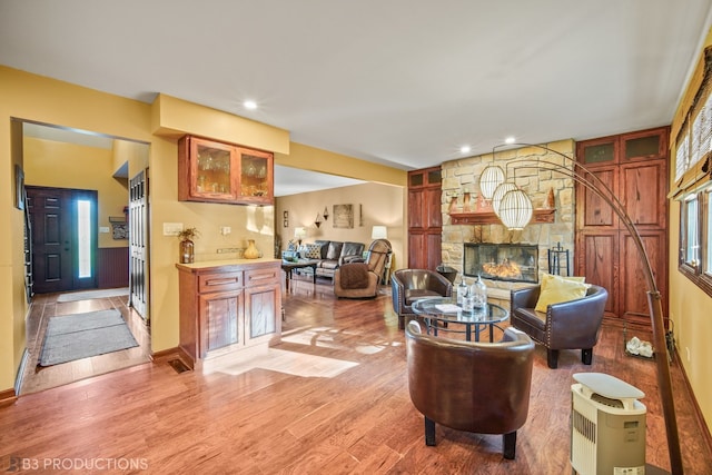 living room with light hardwood / wood-style flooring, indoor bar, and a fireplace