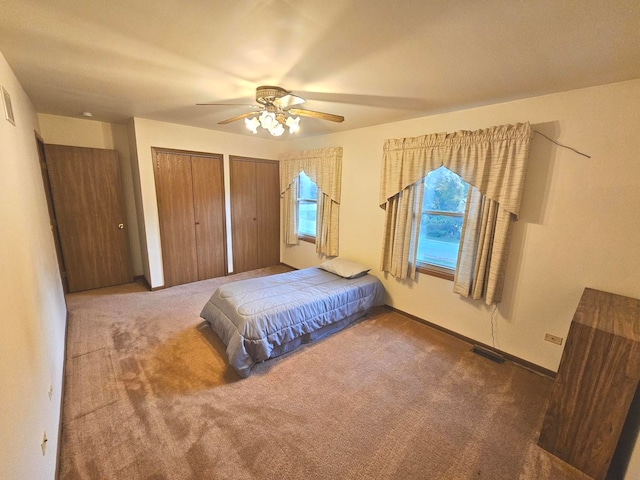 carpeted bedroom with multiple closets and ceiling fan