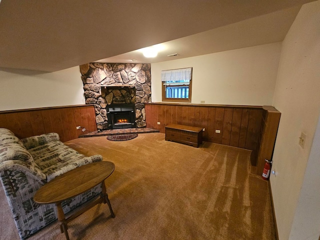 carpeted living room with wooden walls and a fireplace