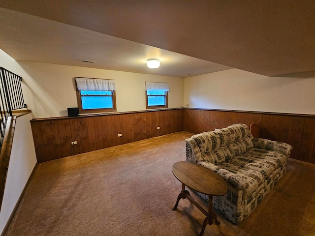 living area with carpet and wooden walls