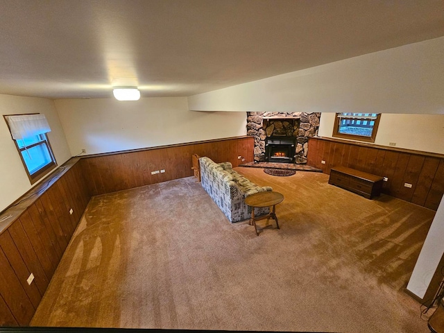 living room featuring wooden walls, a fireplace, and carpet flooring