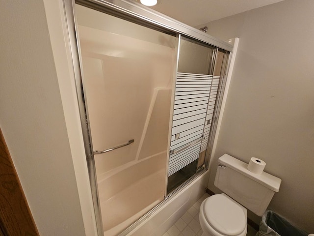 bathroom featuring toilet and bath / shower combo with glass door