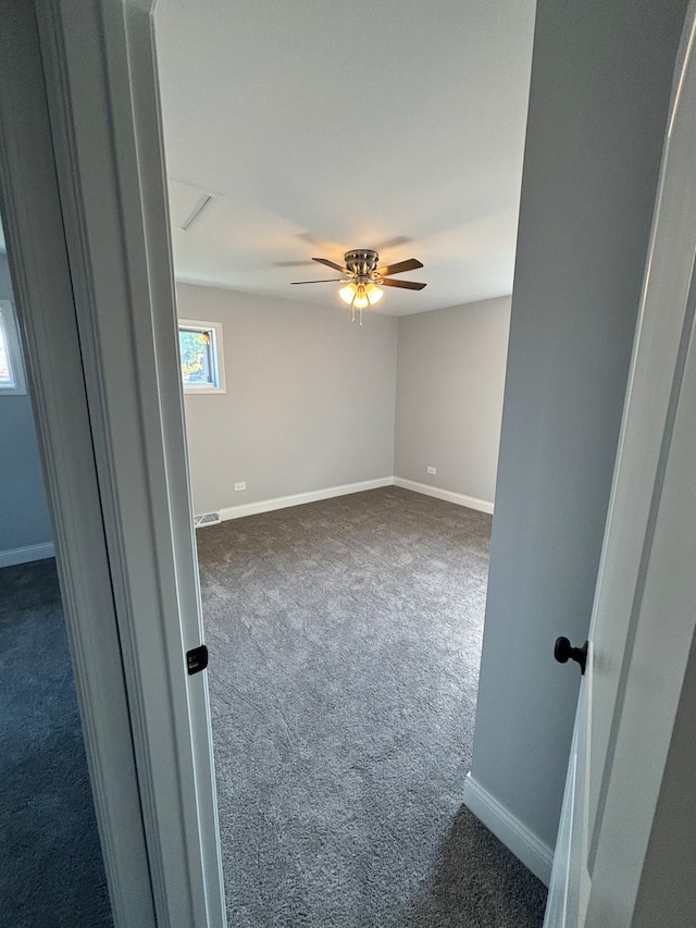 unfurnished room with dark colored carpet and ceiling fan