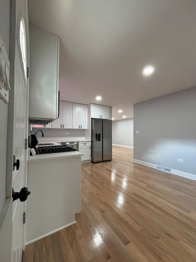 kitchen featuring appliances with stainless steel finishes, sink, light wood-type flooring, and white cabinetry