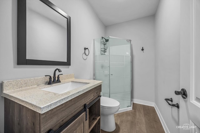 bathroom featuring wood-type flooring, walk in shower, vanity, and toilet