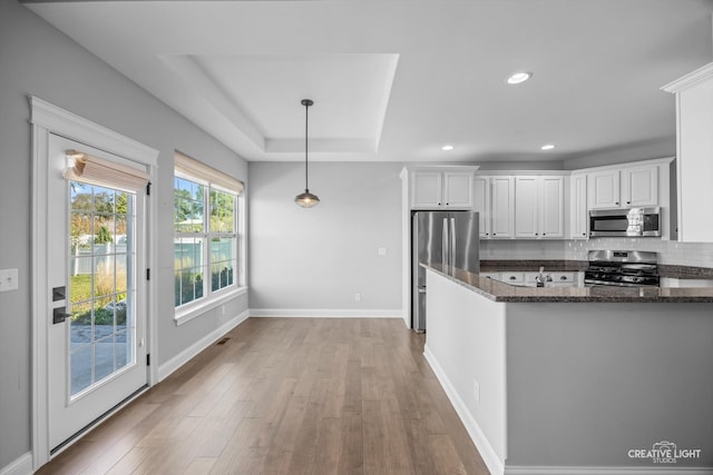 kitchen with light wood-type flooring, tasteful backsplash, decorative light fixtures, stainless steel appliances, and white cabinets