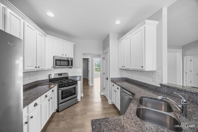 kitchen with white cabinetry, sink, stainless steel appliances, and light hardwood / wood-style flooring