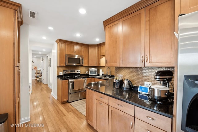 kitchen featuring sink, tasteful backsplash, dark stone counters, washer / dryer, and appliances with stainless steel finishes