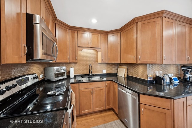 kitchen with decorative backsplash, sink, stainless steel appliances, and dark stone counters