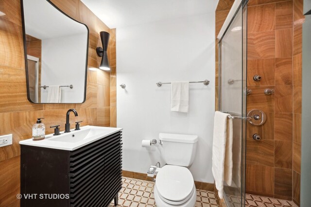 bathroom featuring vanity, toilet, a shower with door, and backsplash