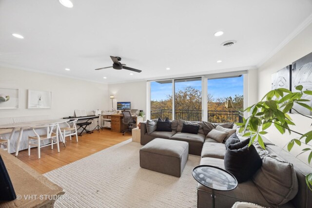 living room with light wood-type flooring, expansive windows, ceiling fan, and ornamental molding