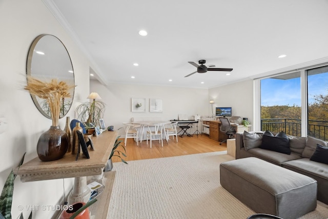 living room featuring ceiling fan, expansive windows, crown molding, and light hardwood / wood-style flooring