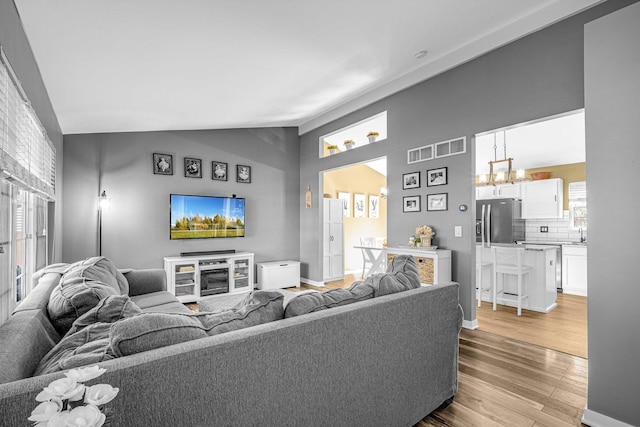 4661 W Tulip Ave, Monee, IL 60449 - living room with light wood-type flooring, lofted ceiling, a chandelier, and baseboards