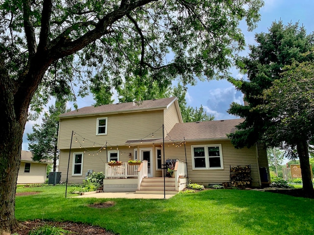 back of property with a deck, a yard, and central AC