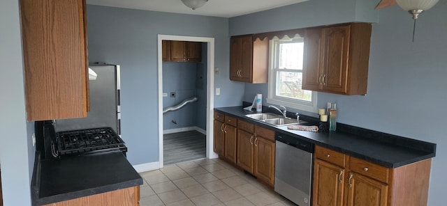 kitchen with stainless steel dishwasher, black stove, light tile patterned floors, and sink