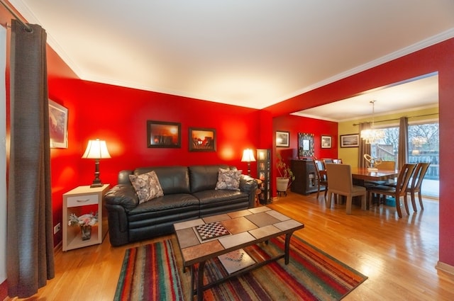 living room featuring wood-type flooring, ornamental molding, and a notable chandelier