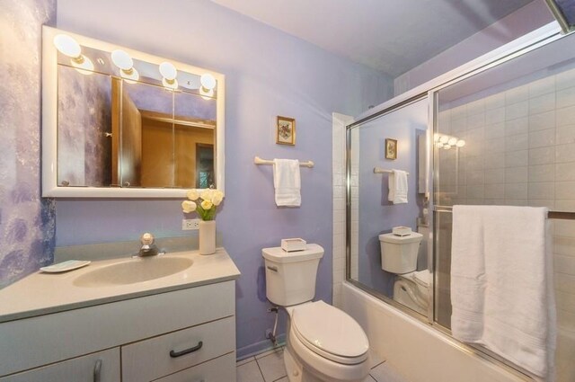 full bathroom with tile patterned flooring, vanity, combined bath / shower with glass door, and toilet