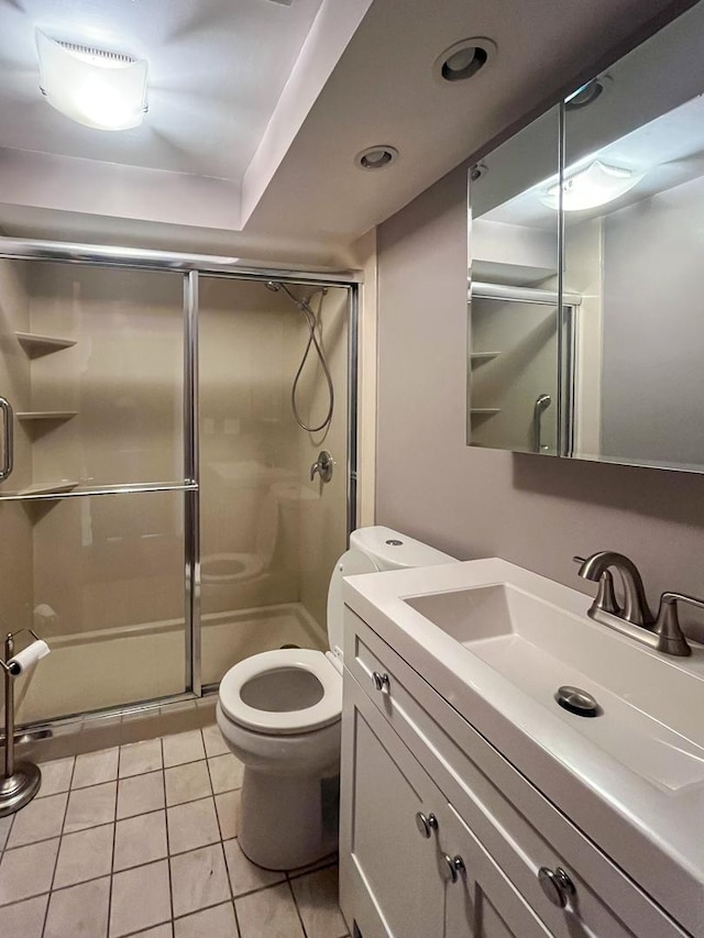 bathroom with vanity, toilet, a shower with shower door, and tile patterned flooring