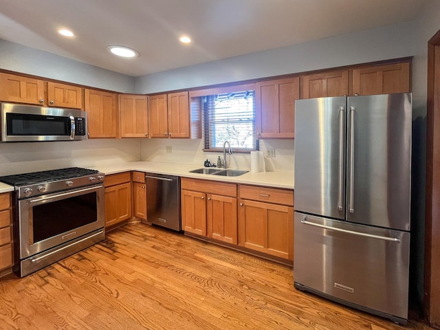 kitchen featuring stainless steel appliances, sink, and light hardwood / wood-style flooring