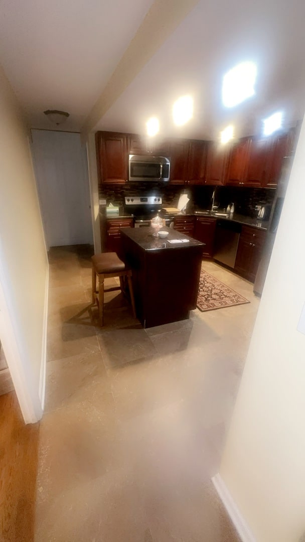 kitchen with stainless steel appliances, backsplash, a kitchen island, and sink