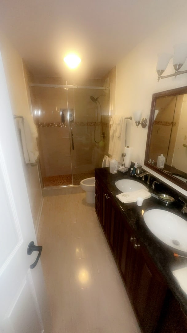 bathroom with vanity, toilet, and a shower with door