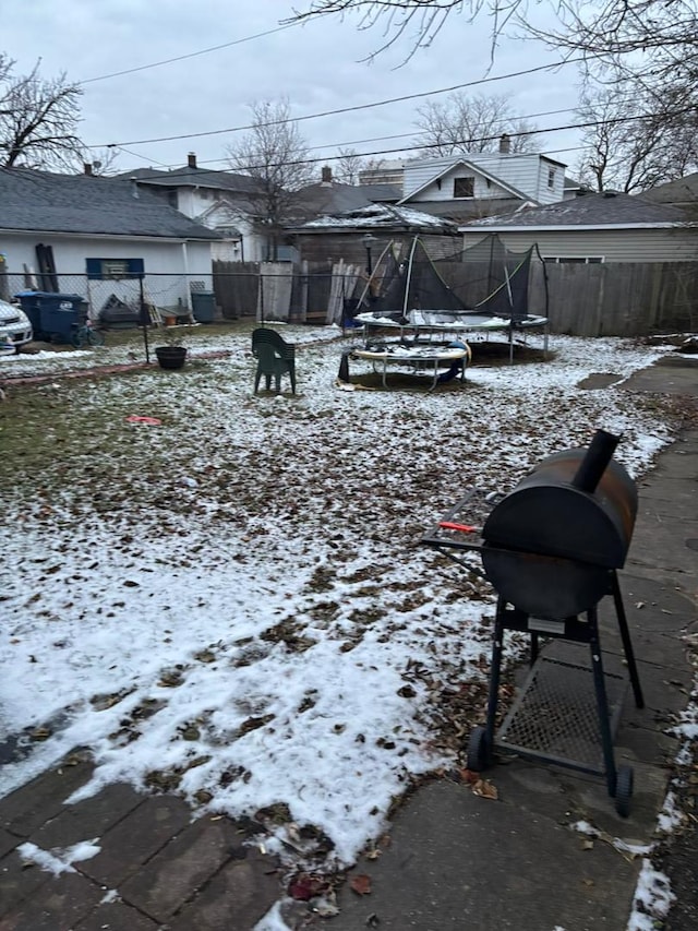 yard covered in snow with a trampoline