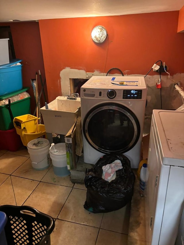 laundry room featuring tile patterned flooring, washer and clothes dryer, and sink