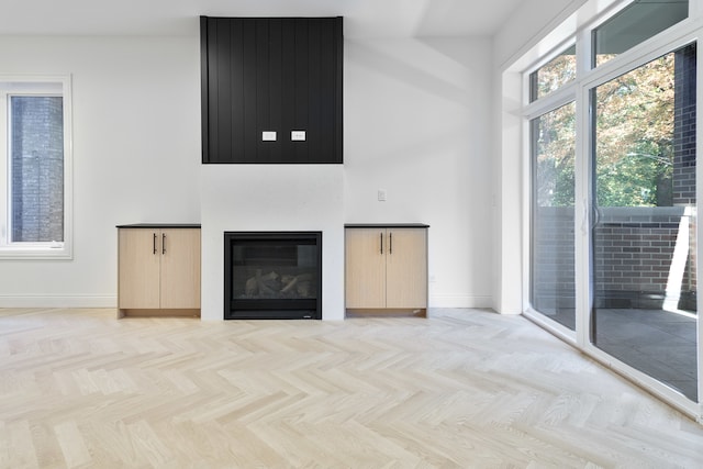 unfurnished living room with a fireplace and light parquet floors