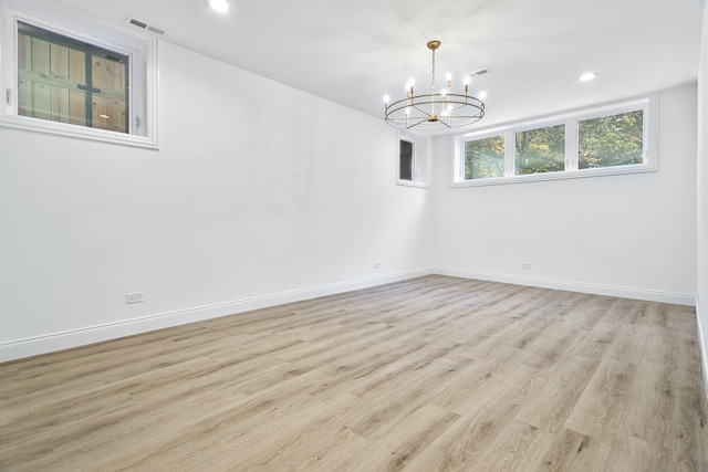 unfurnished room featuring light hardwood / wood-style floors and an inviting chandelier