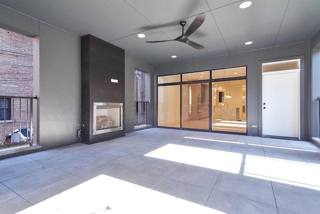 unfurnished living room with ceiling fan, tile patterned floors, and a fireplace