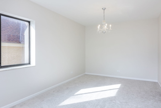 empty room featuring a notable chandelier and carpet flooring