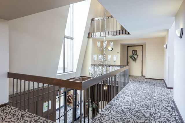 hall featuring an inviting chandelier and carpet flooring