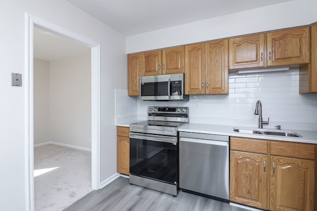 kitchen featuring stainless steel appliances, tasteful backsplash, sink, and light wood-type flooring