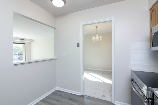 interior space with wood-type flooring, backsplash, and a notable chandelier