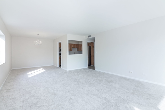 carpeted empty room with an inviting chandelier