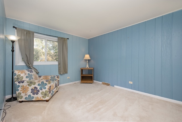 sitting room with ornamental molding and carpet flooring