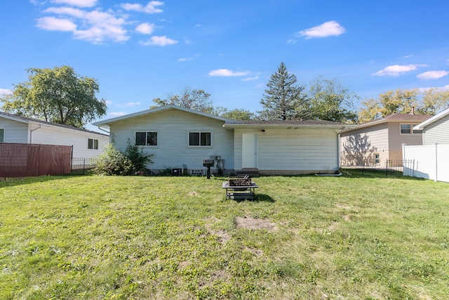 rear view of house with a lawn and an outdoor fire pit