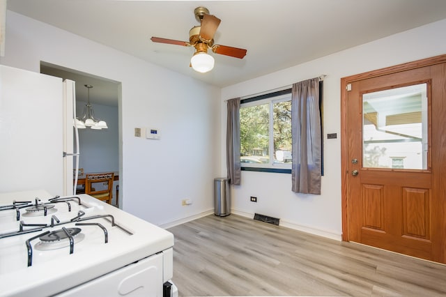 interior space featuring ceiling fan with notable chandelier and light hardwood / wood-style flooring