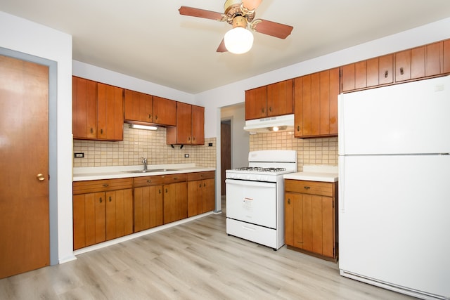 kitchen with white appliances, backsplash, and light hardwood / wood-style flooring