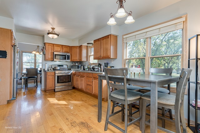 kitchen with light wood-type flooring, a wealth of natural light, a chandelier, and stainless steel appliances