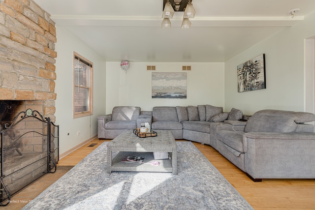 living room featuring a stone fireplace and light wood-type flooring