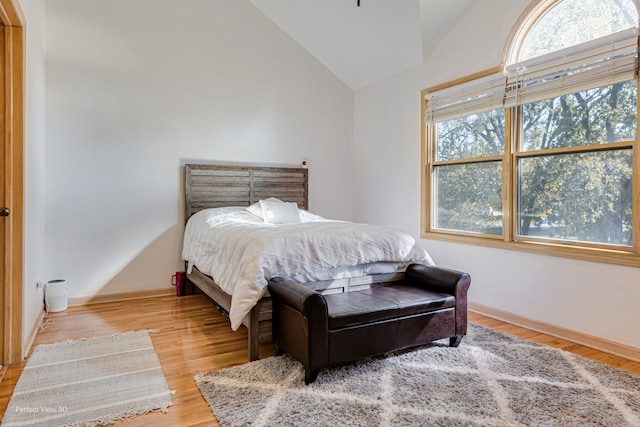 bedroom featuring high vaulted ceiling and hardwood / wood-style floors