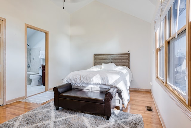 bedroom with light hardwood / wood-style flooring, ensuite bath, and high vaulted ceiling