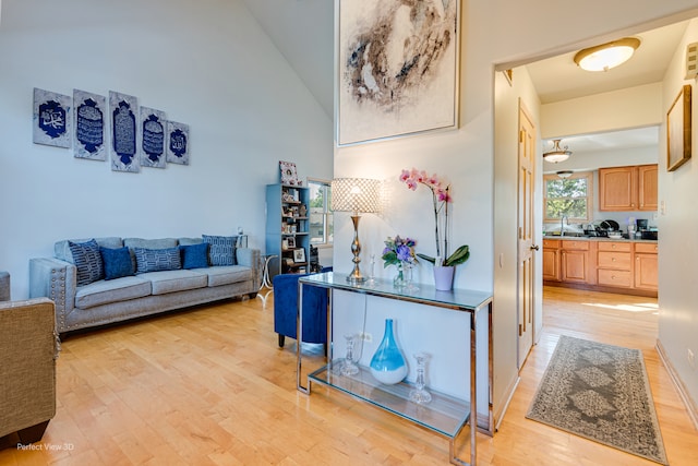 hallway featuring sink, light hardwood / wood-style floors, and high vaulted ceiling