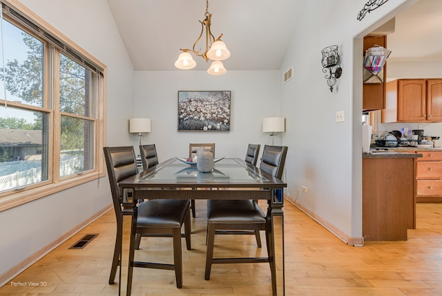 dining room with lofted ceiling, light hardwood / wood-style floors, and a chandelier