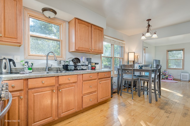 kitchen with a healthy amount of sunlight, hanging light fixtures, sink, and light hardwood / wood-style floors