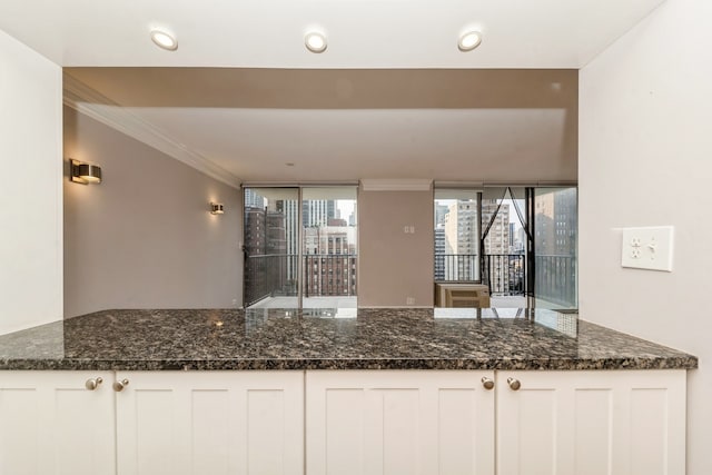 kitchen with crown molding, white cabinets, and dark stone counters