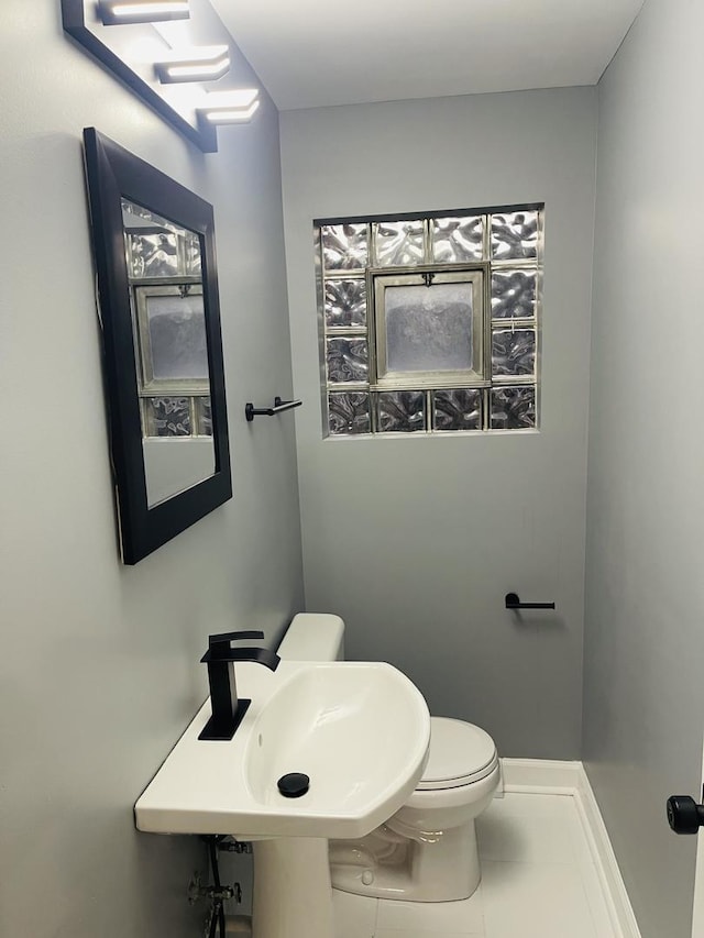 1409 E 90th St, Chicago, IL 60619 - half bathroom with tile patterned flooring, toilet, baseboards, and a sink