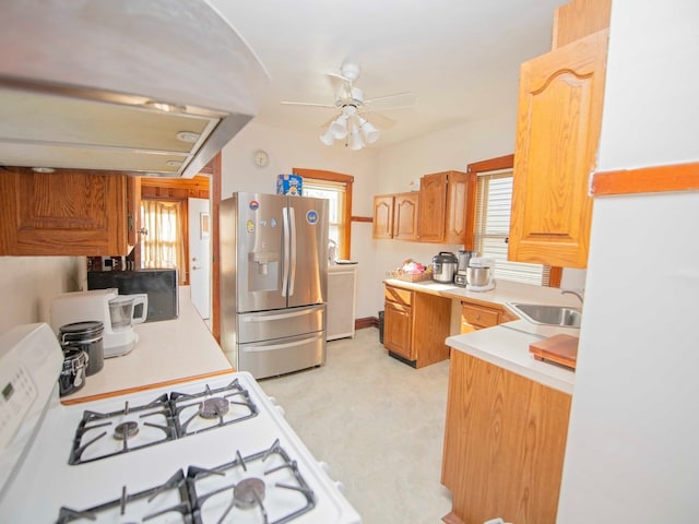 kitchen with ceiling fan, sink, island range hood, white range with gas stovetop, and stainless steel fridge with ice dispenser